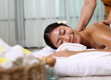 Young Asian woman receiving an oil massage on her back at spa salon by professional masseuse, Spa treatment and aroma oil massage concept